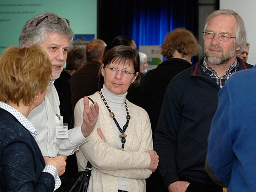 Auftakt 29plusplus Themeninseln Foto: Einige Teilnehmer der Auftaktveranstaltung unterhalten sich an einer der Themeninseln mit einem Mitarbeiter des Landratsamtes.