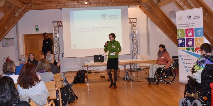 Die Vorsitzende des Behindertenbeirats Dr. Frauke Schwaiblmair spricht ein Grußwort; rechts neben ihr: die Organisatorin des Netzwerktreffens, Sigrid Karl, Beauftragte für Menschen mit Behinderung im Landkreis München.