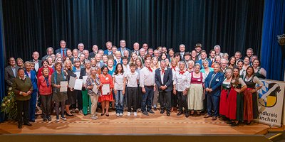 Foto: Alle Geehrten der Sozialehrung 2025 auf einer Bühne mit Landrat Christoph Göbel und zahlreichen Gratulanten.