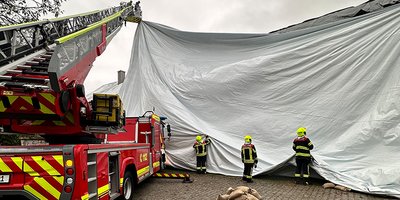 Foto: Feuerwehrkräfte aus dem Landkreis München bringen ein Notdach an.