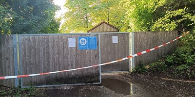 Foto: Der Eingangsbereich der FKK-Halbinsel am Feringasee ist mit einem rot-weißen Absperrband von links nach rechts abgesperrt.