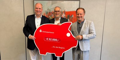 Landrat Christoph Göbel, Vorstandsvorsitzender der Kreissparkasse Andreas Frühschütz und Landrat Robert Niedergesäß (Ebersberg) halten einen roten Scheck in Form eines Sparschweins in die Kamera.
